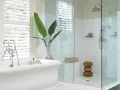 Bagno elegante con vasca freestanding e doccia con ampie dimensioni. Piante verdi e dettagli in mosaico completano l'ambiente.