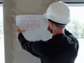 Un ingegnere con casco bianco esamina un progetto, segno che i migliori general contractor pianificano ogni dettaglio.