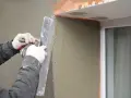 Lavori di intonacatura attorno alle spallette delle finestre, con un operaio che stende il materiale.