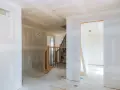 Interni in fase di finitura, con pareti pronte per essere rivestite con cartongesso senza telaio. Scala in legno e metallo.