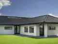 Casa moderna con tetto a padiglione scuro, finestre a tetto e prato verde.