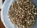 Granuli di vermiculite espansa isolante termico in un secchio bianco. Materiale leggero e poroso, ideale per l'edilizia.