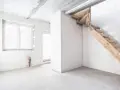 Interno grezzo con finestre, scala in legno grezzo e un tubo blu. L'altezza taverna è ancora da definire.