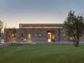 Villetta moderna in pietra, con prato curato e alberi. Un esempio di come potrebbe essere quanto costa costruire una villetta di 120 mq.