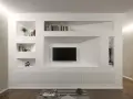 Parete attrezzata moderna con nicchie per libri e TV, realizzata in cartongesso doppia lastra, con mobili contenitori a scomparsa.