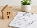 Modello di casa in legno accanto a un checklist documenti, ideale per un esempio capitolato casa nuova costruzione.