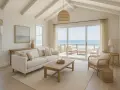 Soggiorno luminoso con vista mare, perfetto per idee ristrutturazione casa al mare. Divano bianco, tavolino in legno e poltrona in rattan creano un'atmosfera rilassante.