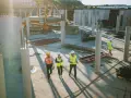 Un cantiere edile con operai in giubbotti ad alta visibilità. Il general contractor cos'è? È chi coordina i lavori, gestendo fornitori e tempi per un progetto di successo.