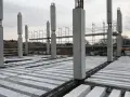 Costruzione in corso con pilastri in cemento e solai prefabbricati in attesa di completamento.