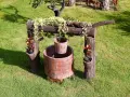 Pozzo decorativo in mattoni con secchio appeso, circondato da verde. Un'idea per capire quanto costa fare un pozzo.