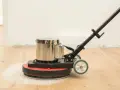 Macchina levigatrice in azione per levigare parquet fai da te. La polvere bianca indica il lavoro in corso.