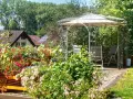 Un gazebo con un pavimento in legno fai da te, circondato da fiori colorati e vegetazione lussureggiante.