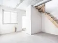 Interno grezzo con finestra, porta finestra e scala in legno grezzo. Ambiente in fase di ristrutturazione, un futuro piano seminterrato.
