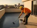 Operaio con casco giallo applica impermeabilizzante su un terrazzo, un vero rifacimento terrazzo a regola d'arte.