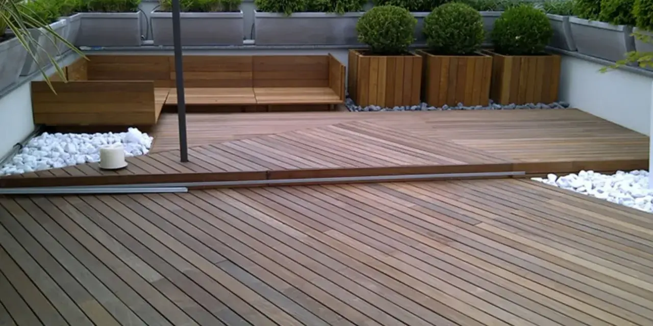 Un balcone trasformato con un pavimento in legno fai da te, circondato da piante e arredi moderni.