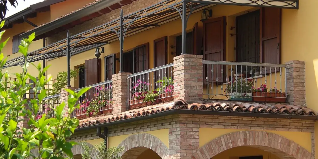 Il montaggio scossalina balcone protegge la facciata. Balcone fiorito con ringhiera in ferro battuto e tettoia decorata.