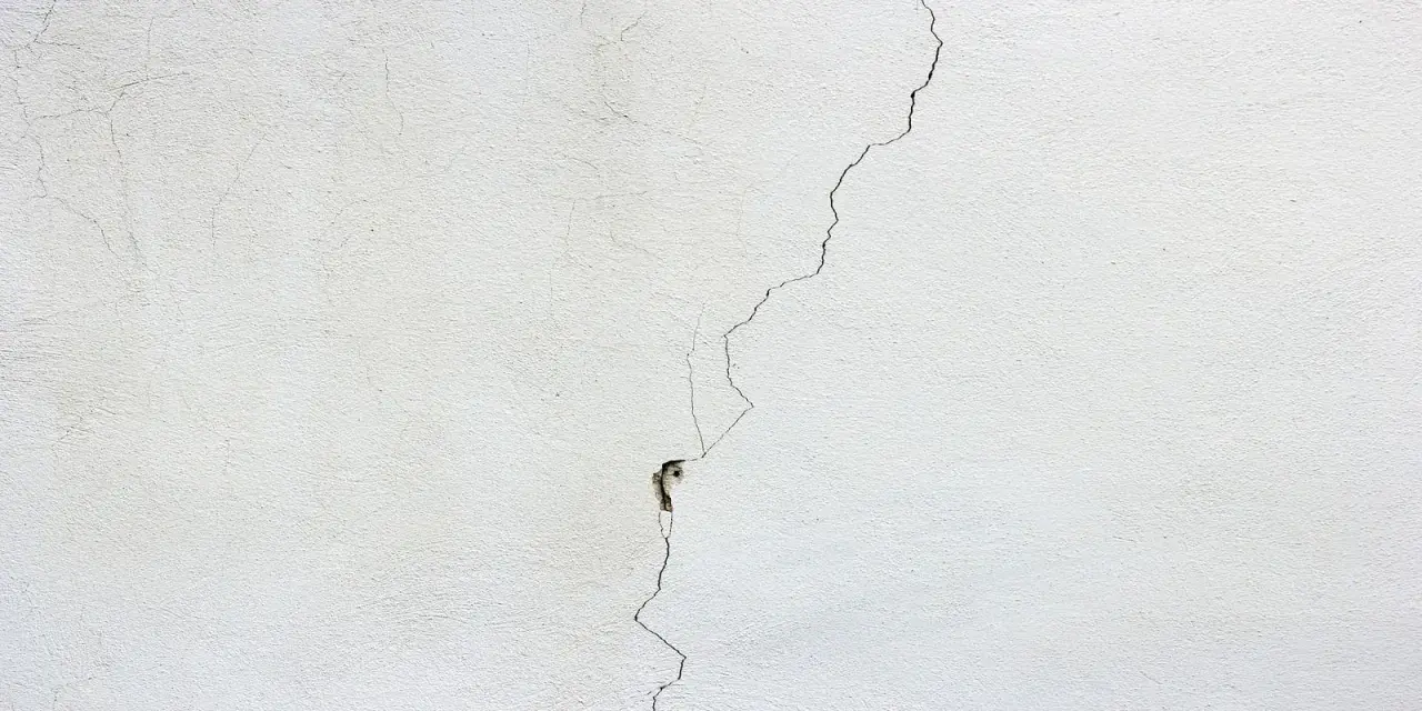 Crepa profonda su muro bianco, un segno per come distinguere le crepe pericolose.