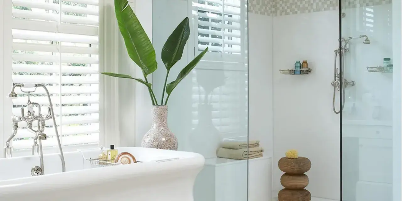 Bagno elegante con vasca freestanding e doccia con ampie dimensioni. Piante verdi e dettagli in mosaico completano l'ambiente.