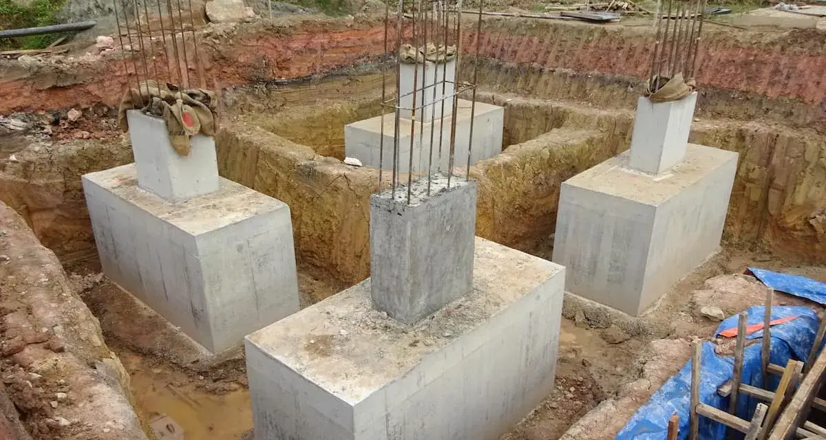 Scavi per il consolidamento fondazioni con pilastri in cemento armato e armature in vista.