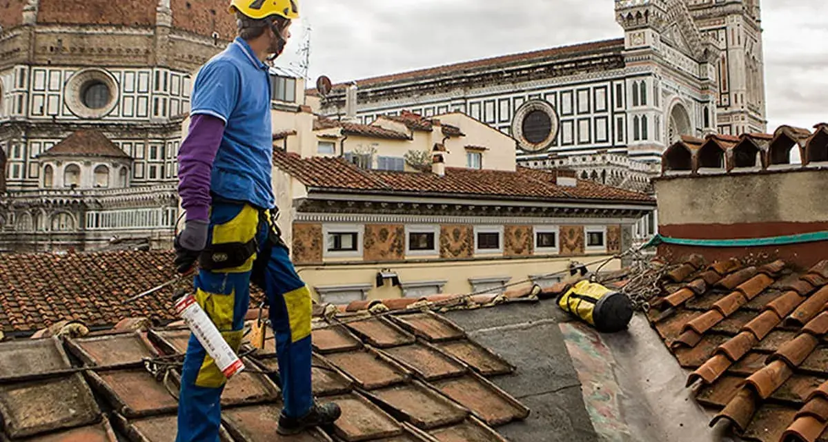 Operaio sul tetto di Firenze, valuta il costo coibentazione tetto esistente. Lavori in quota con vista Duomo.