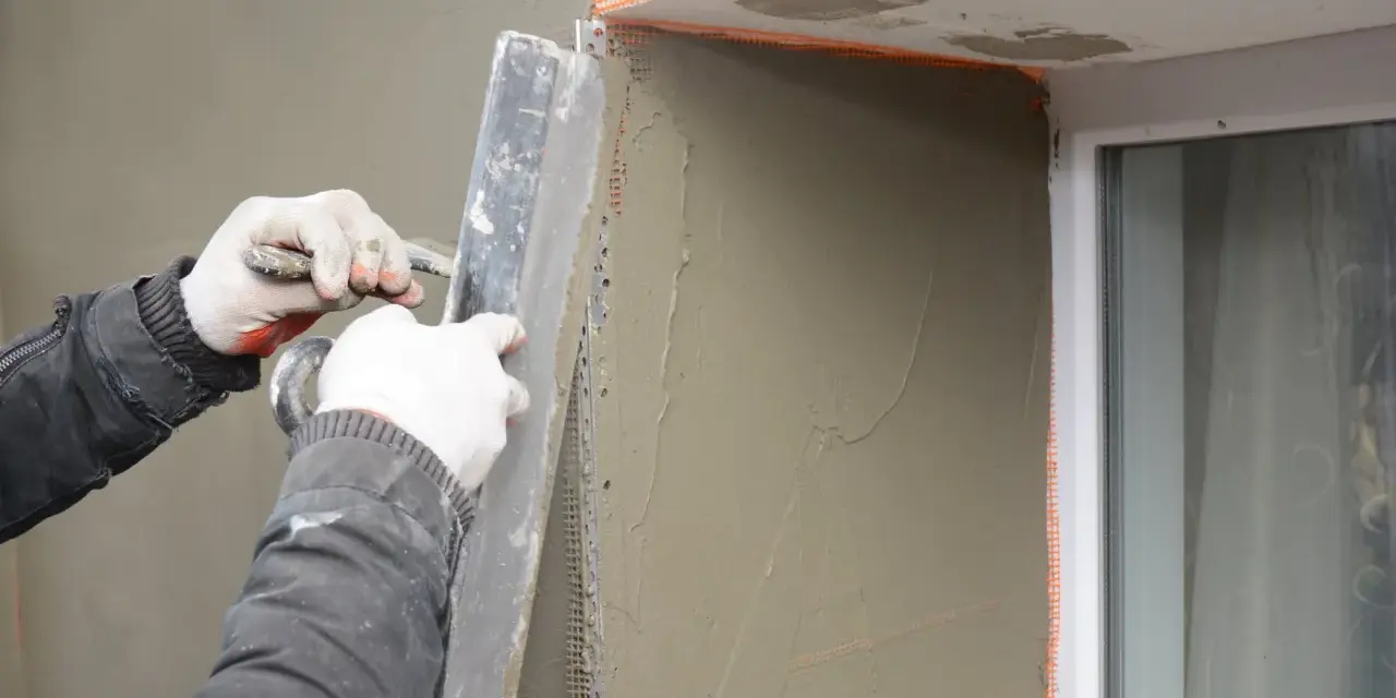 Lavori di intonacatura attorno alle spallette delle finestre, con un operaio che stende il materiale.