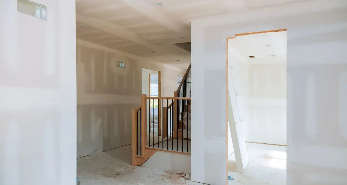 Interni in fase di finitura, con pareti pronte per essere rivestite con cartongesso senza telaio. Scala in legno e metallo.