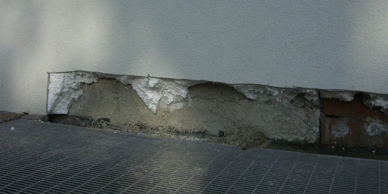 Deterioramento di un muro con esposizione di materiale isolante in eps alta densità e grata metallica sottostante.