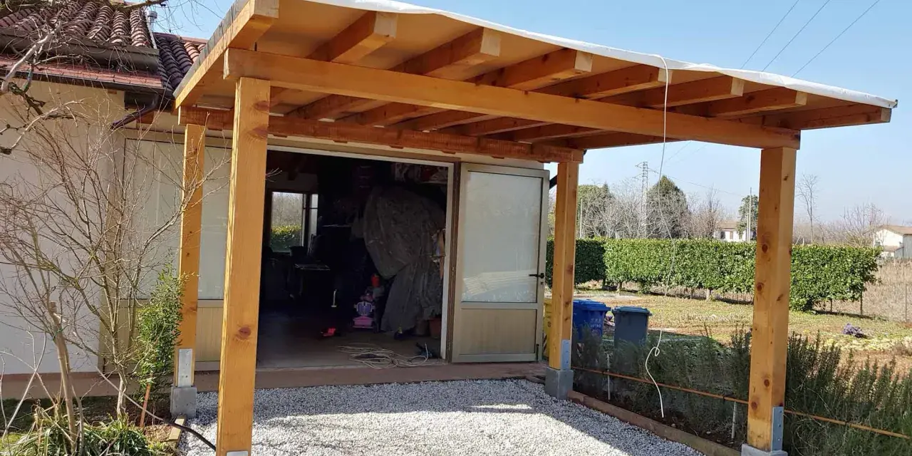 Una tettoia fai da te in legno protegge un'entrata, con un tetto in telo bianco e pilastri robusti.