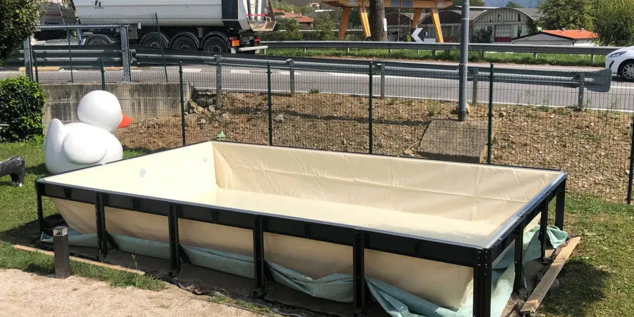 Piscina seminterrata in fase di installazione, con un grande anatroccolo gonfiabile sullo sfondo. Si attendono i permessi per completare il progetto.
