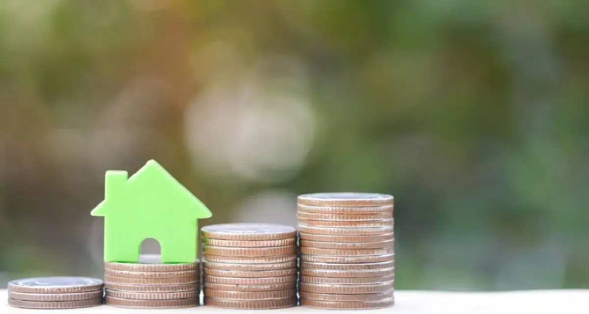 Una casa verde su pile di monete, un'immagine che simboleggia come funziona il Superbonus 110 per l'edilizia.
