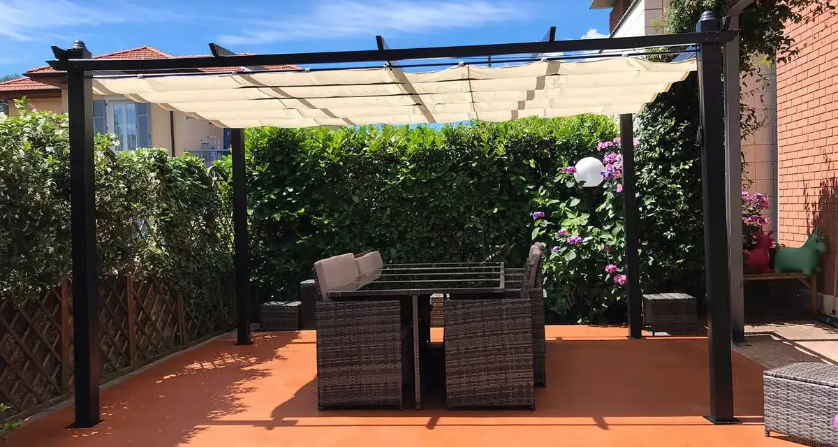Un patio con tavolo e sedie sotto una pergola, con un **pavimento esterno economico fai da te** color terracotta.