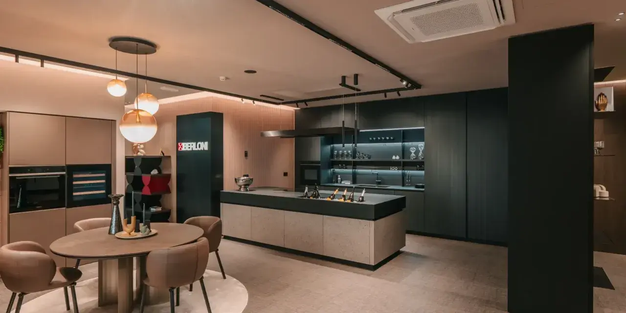 Elegante cucina scura con isola centrale e un tavolo rotondo. Il pavimento chiaro crea un contrasto moderno e luminoso.
