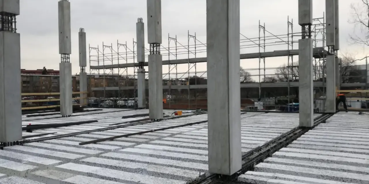 Costruzione in corso con pilastri in cemento e solai prefabbricati in attesa di completamento.