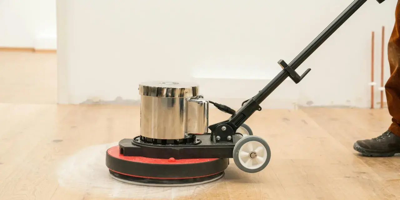 Macchina levigatrice in azione per levigare parquet fai da te. La polvere bianca indica il lavoro in corso.