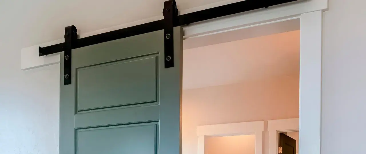 Trasformare porta battente in scorrevole: una porta verde acqua con binario nero, un'elegante soluzione moderna per ottimizzare gli spazi.
