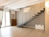 Moderna scala a sbalzo, soluzione per chi ha una scala troppo ripida. Arredamento minimalista con mobili in legno e tessuti chiari.