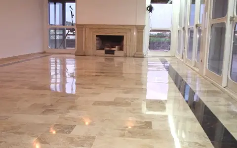 Pavimento in marmo beige con finitura a specchio, che riflette le luci e le finestre. Un lavoro di lucidatura perfetto per un ambiente elegante.