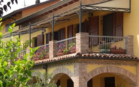 Il montaggio scossalina balcone protegge la facciata. Balcone fiorito con ringhiera in ferro battuto e tettoia decorata.