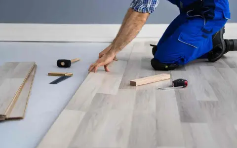 Installazione di un nuovo pavimento in laminato, un passo fondamentale per come isolare il pavimento dal freddo. Attrezzi da lavoro a portata di mano.