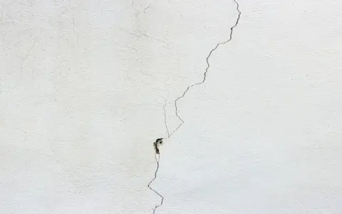 Crepa profonda su muro bianco, un segno per come distinguere le crepe pericolose.