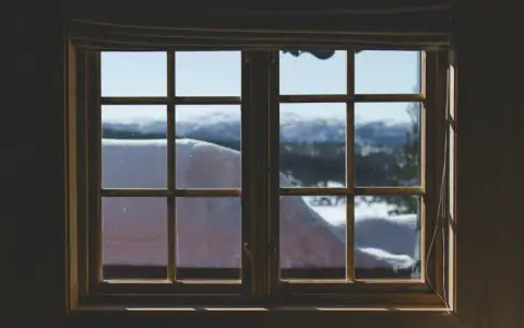 Finestra con infissi in legno, vista su paesaggio innevato. Ideale per chi vuole rinnovare infissi in legno fai da te.