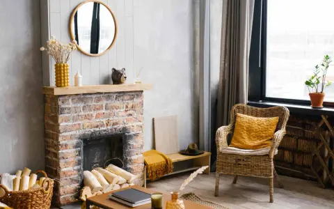 Un camino di mattoni rustico, pronto per essere rinnovato. Legna accatastata, decorazioni e una sedia in vimini invitano al relax.