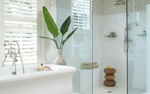 Bagno elegante con vasca freestanding e doccia con ampie dimensioni. Piante verdi e dettagli in mosaico completano l'ambiente.