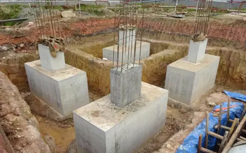 Scavi per il consolidamento fondazioni con pilastri in cemento armato e armature in vista.