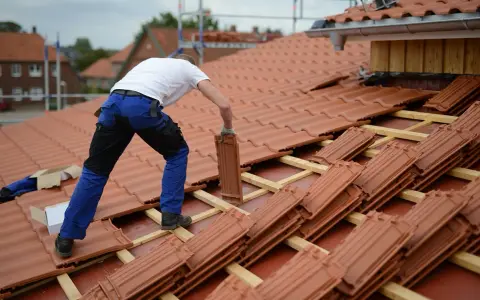 Operaio posa tegole su tetto in fase di rifacimento. Stima quanto costa rifare un tetto di 200 mq.