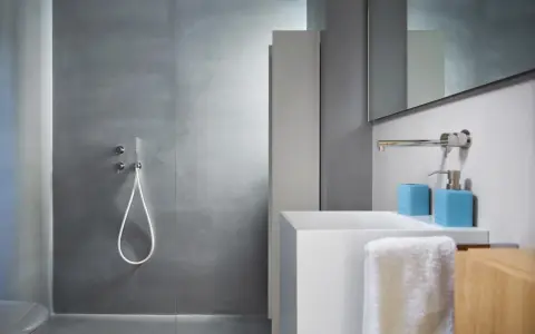 Bagno moderno con rivestimento doccia senza piastrelle effetto resina, lavabo bianco e accessori azzurri.