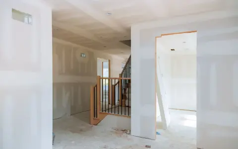 Interni in fase di finitura, con pareti pronte per essere rivestite con cartongesso senza telaio. Scala in legno e metallo.