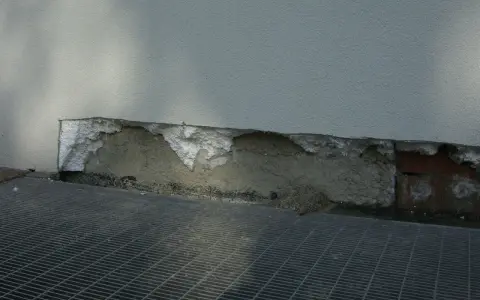 Deterioramento di un muro con esposizione di materiale isolante in eps alta densità e grata metallica sottostante.