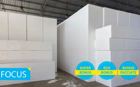 Magazzino con blocchi di polistirolo bianco. La scheda tecnica eps 100 è visibile su alcuni blocchi. Tre cerchi con scritte "Super Bonus", "Eco Bonus" e "Bonus Facciate".