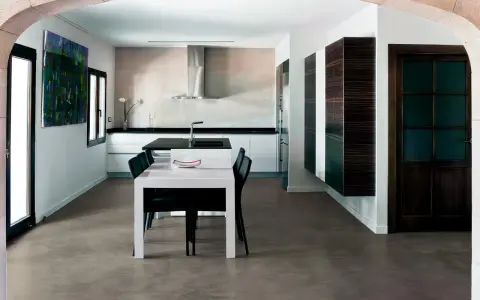 Modern kitchen with a dining area. The **pavimento in cemento per interni costi** is visible, offering a sleek and contemporary look.